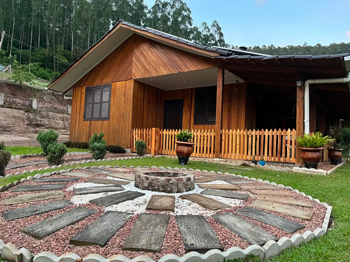 Fachada de madeira e jardim da Cabana Aconchego